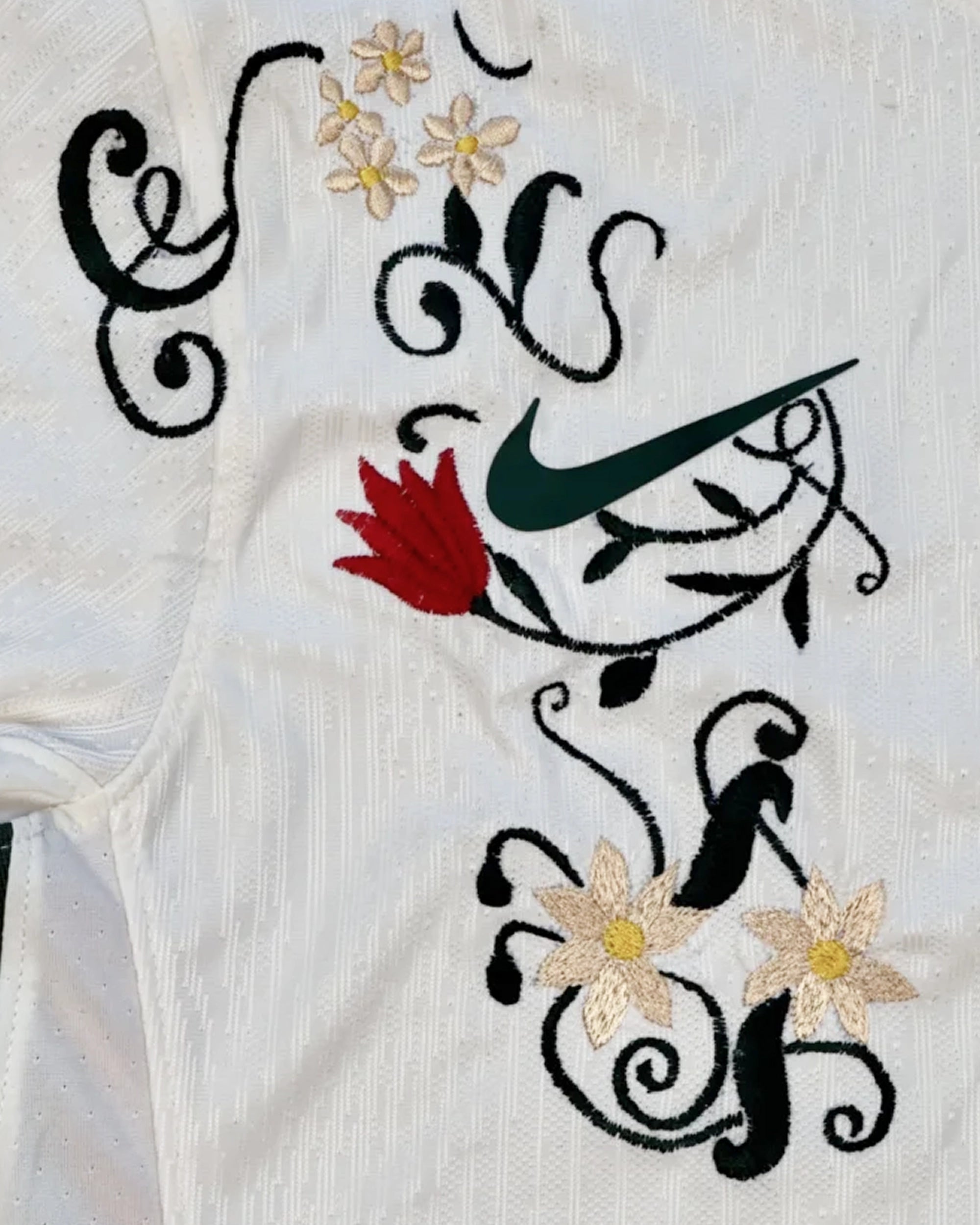 Close-up of the Chelsea crest on the Chelsea Bloom Edition Crest Detail surrounded by red and black botanical stitching.