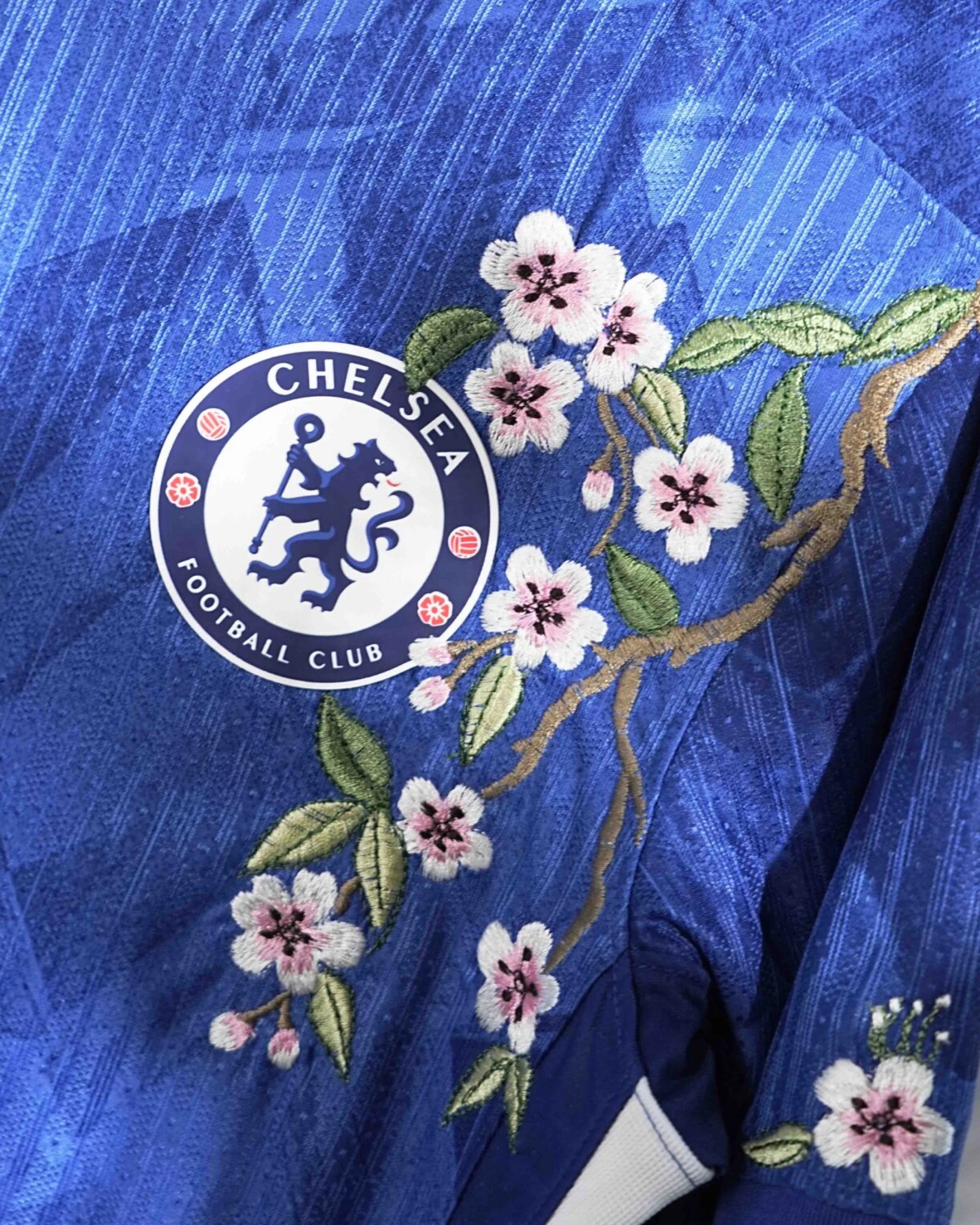 Detailed threadwork on the Chelsea Embroidered Blue Jersey highlighting the sports logo surrounded by bespoke botanical stitching.