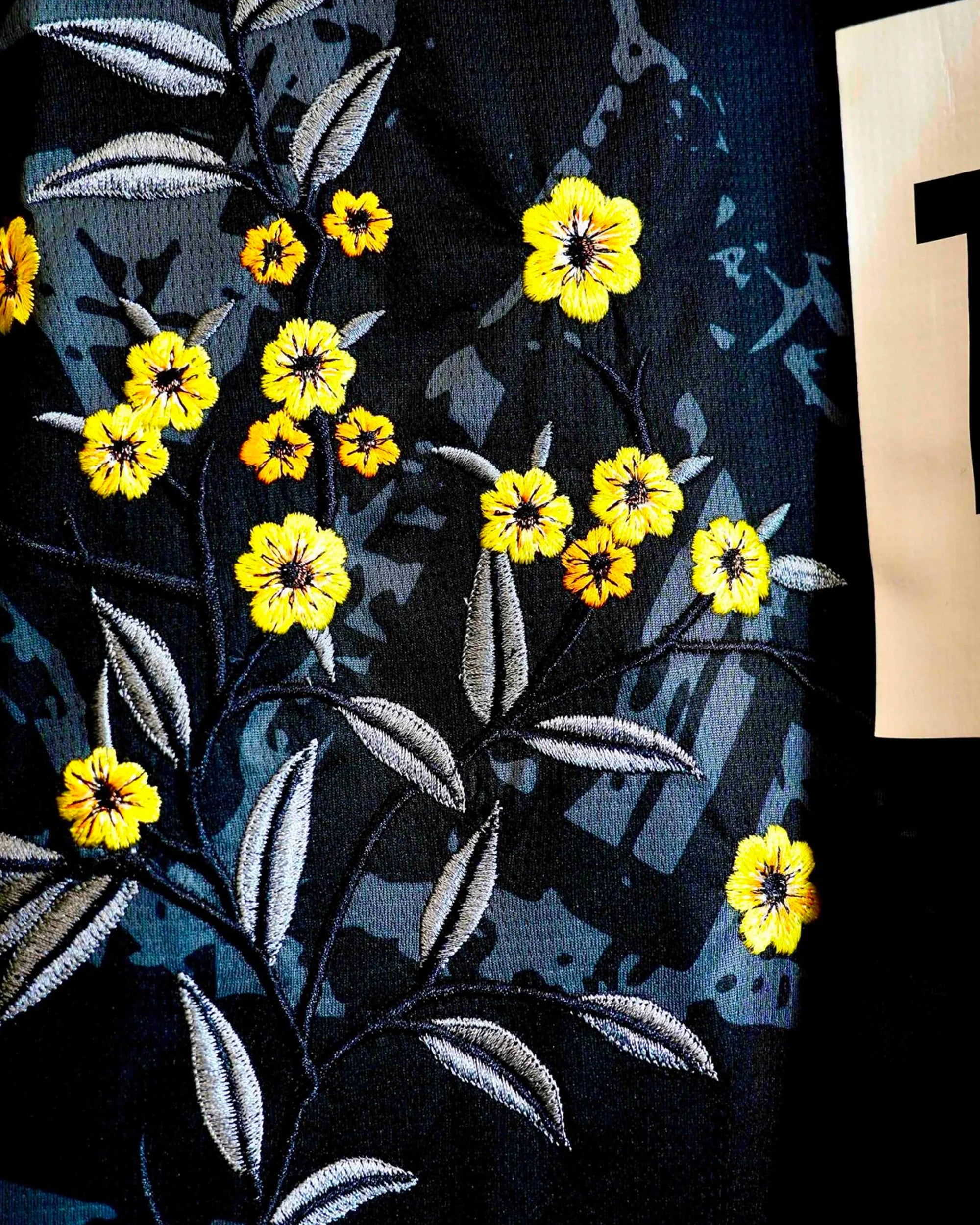 Close-up of the club crest on the Dortmund 'Yellow Bee' Edition Jersey 2022-23, beautifully framed by bespoke black botanical stitching. Perfect detailed embroidery view on this Dortmund Embroidered Jersey.