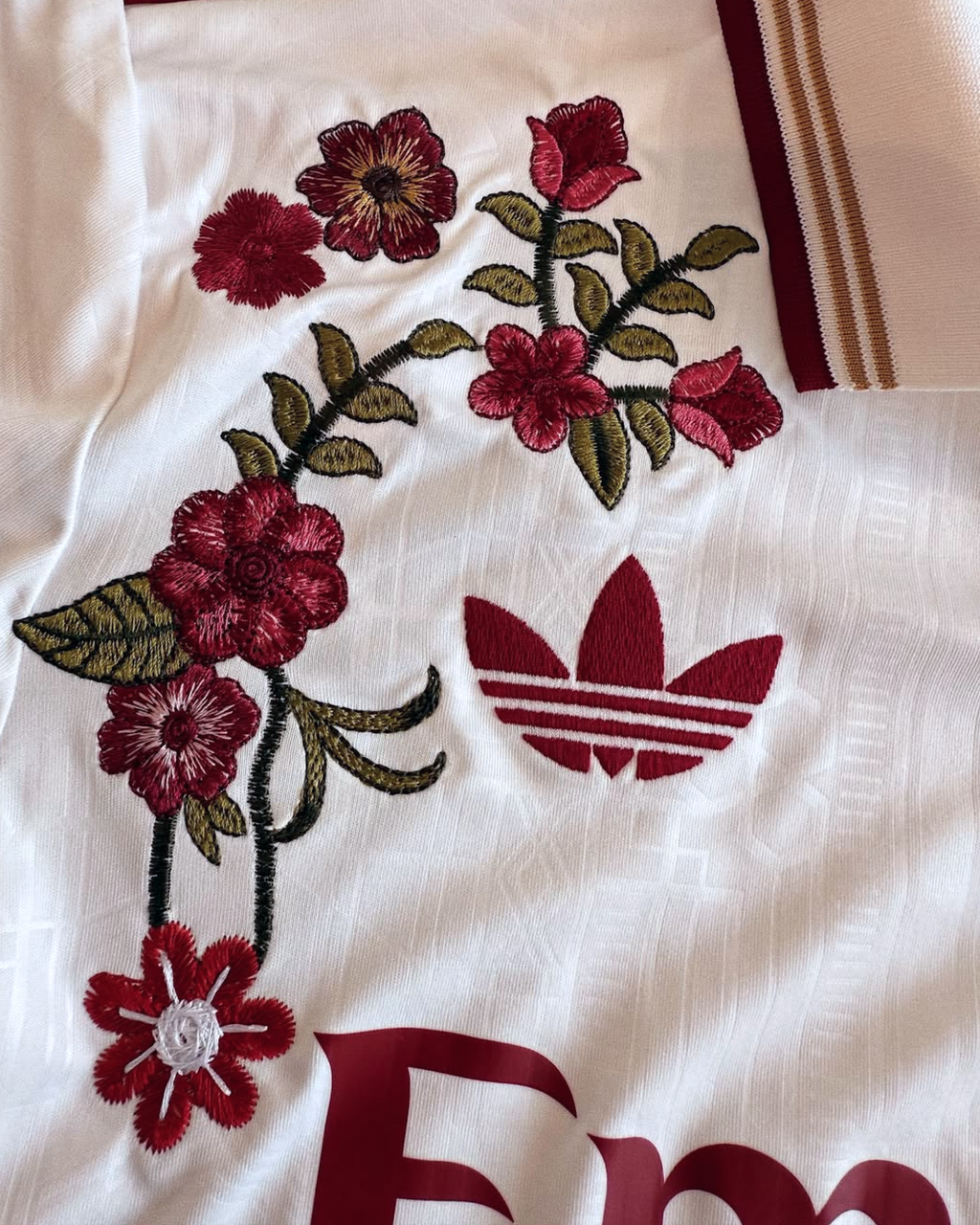 Detailed look at the high-quality red floral craftsmanship on the white textured fabric of the Embroidered Arsenal Third Long Sleeves.