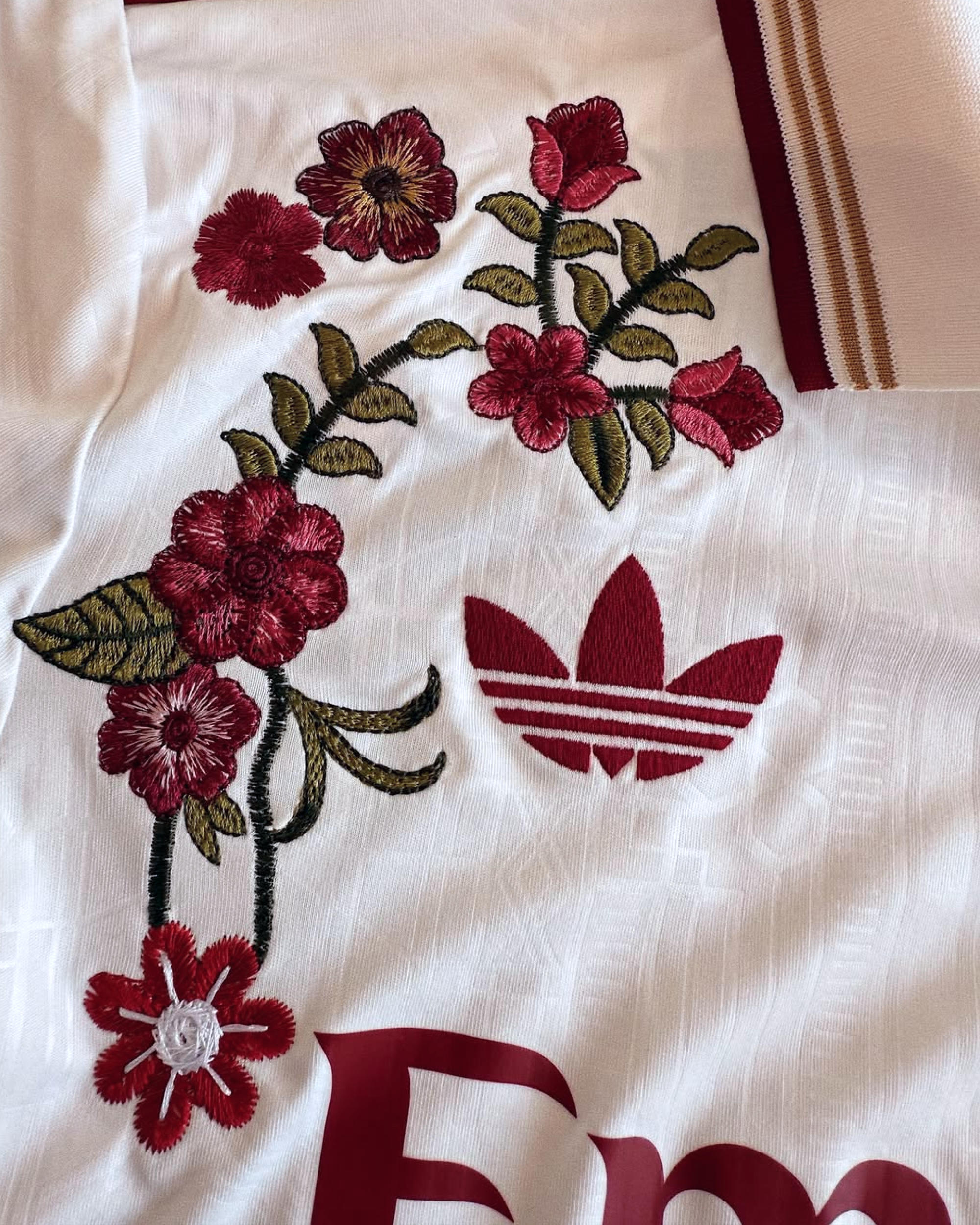 Detailed look at the high-quality red floral craftsmanship on the white textured fabric of the Embroidered Arsenal Third Long Sleeves.