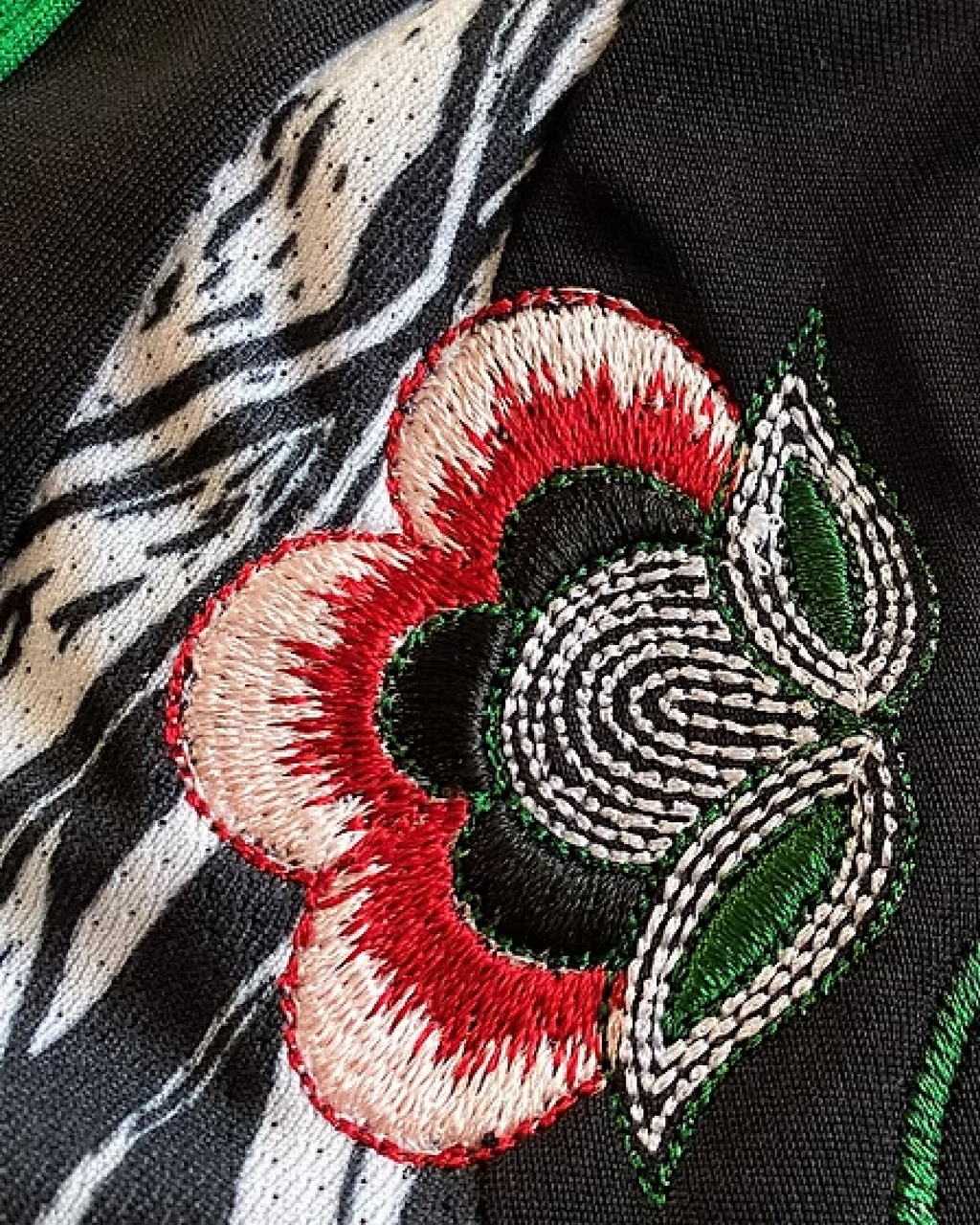 A detailed look at the artistic floral embroidery on the Embroidered Arsenal Away Jersey 2024-25, showcasing rich red, green, and white thread work
