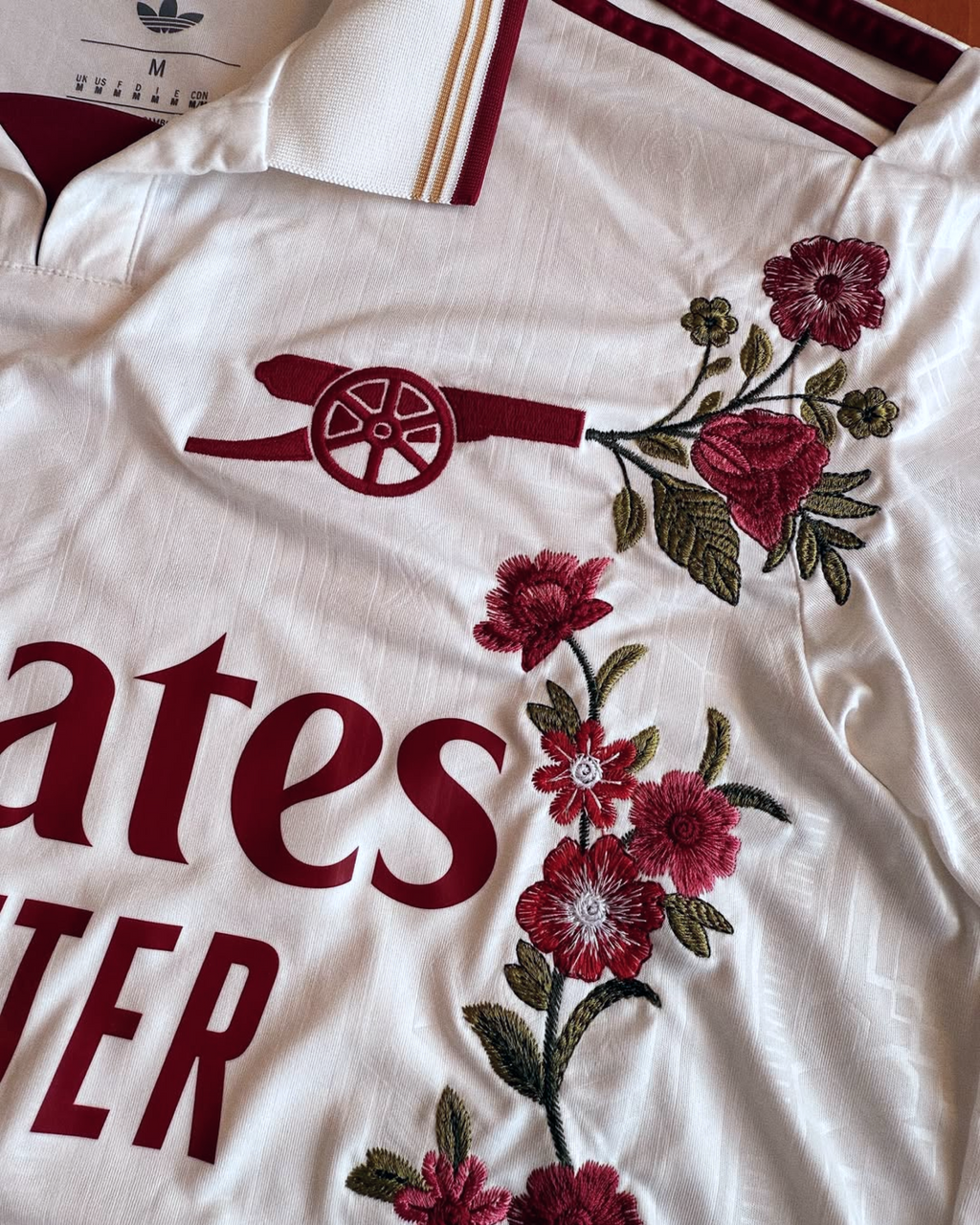 Close-up of the red cannon crest on the Embroidered Arsenal Third Long Sleeves, highlighted by intricate red and white floral embroidery.