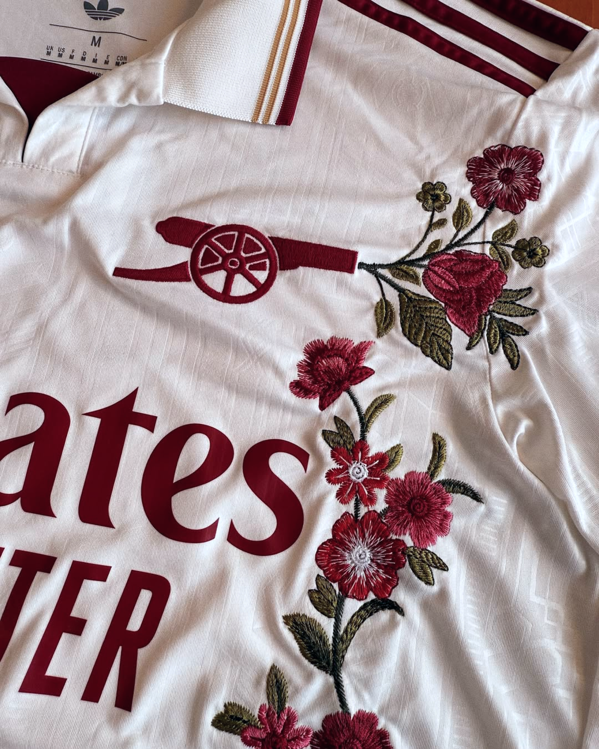 Close-up of the red cannon crest on the Embroidered Arsenal Third Long Sleeves, highlighted by intricate red and white floral embroidery.