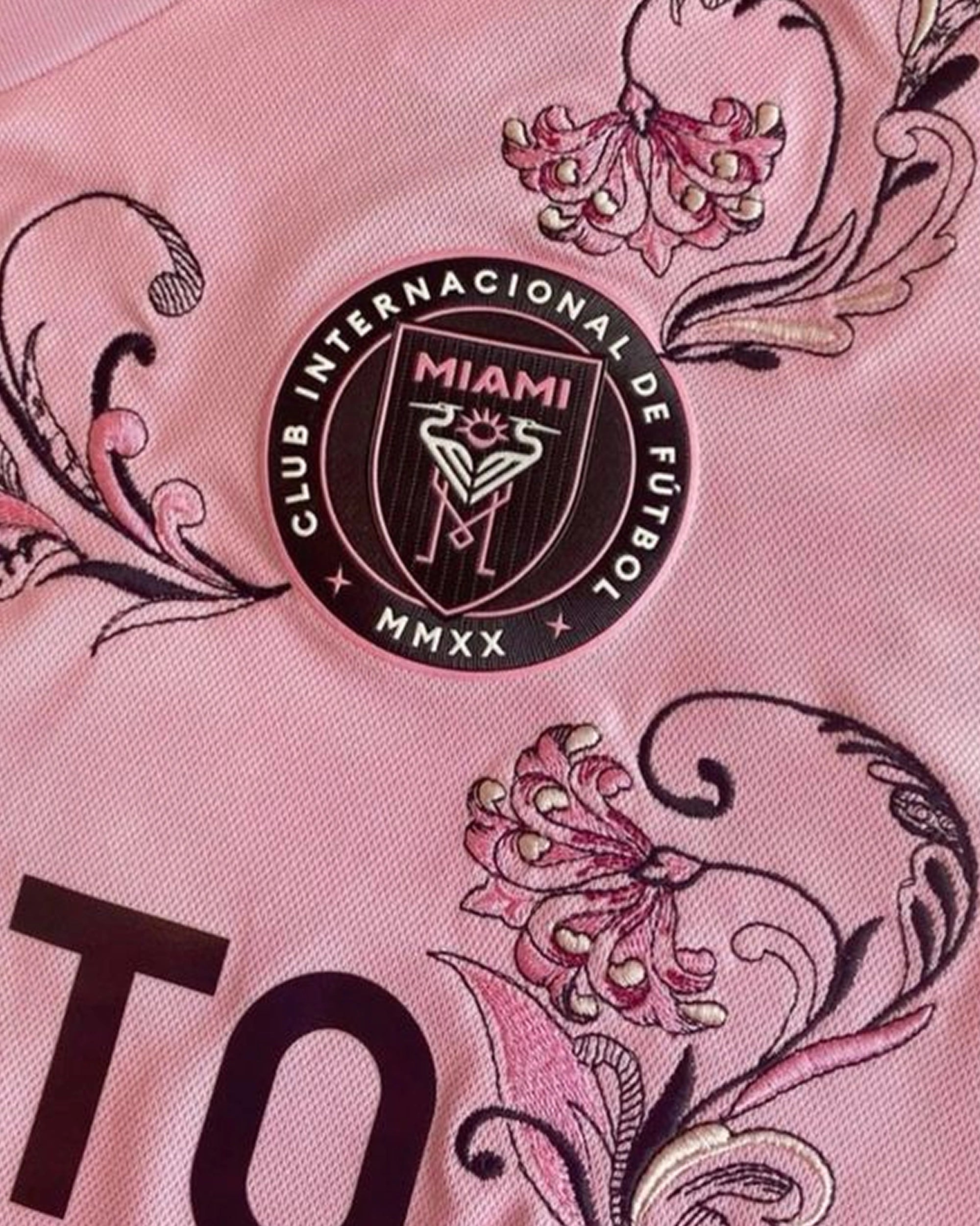 Close-up of the club crest on the Inter Miami Embroidered Jersey, surrounded by intricate pink and black floral art.
