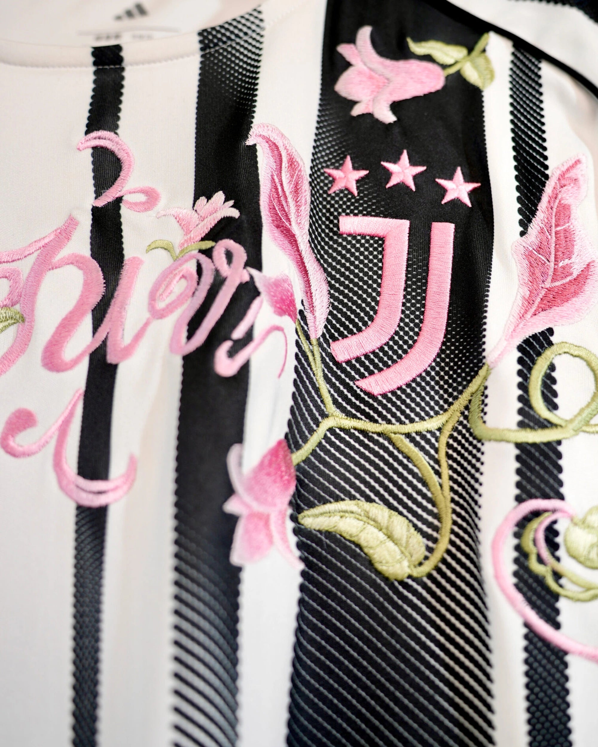 Detailed threadwork on the Juventus Embroidered Pink Jersey highlighting the sports logo surrounded by bespoke botanical stitching.