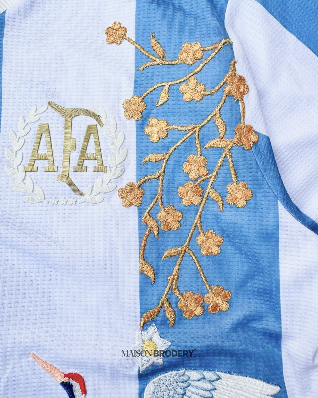 Floral gold embroidery on the Embroidered Argentina 50th Anniversary featuring cherry blossom branches and crest details.