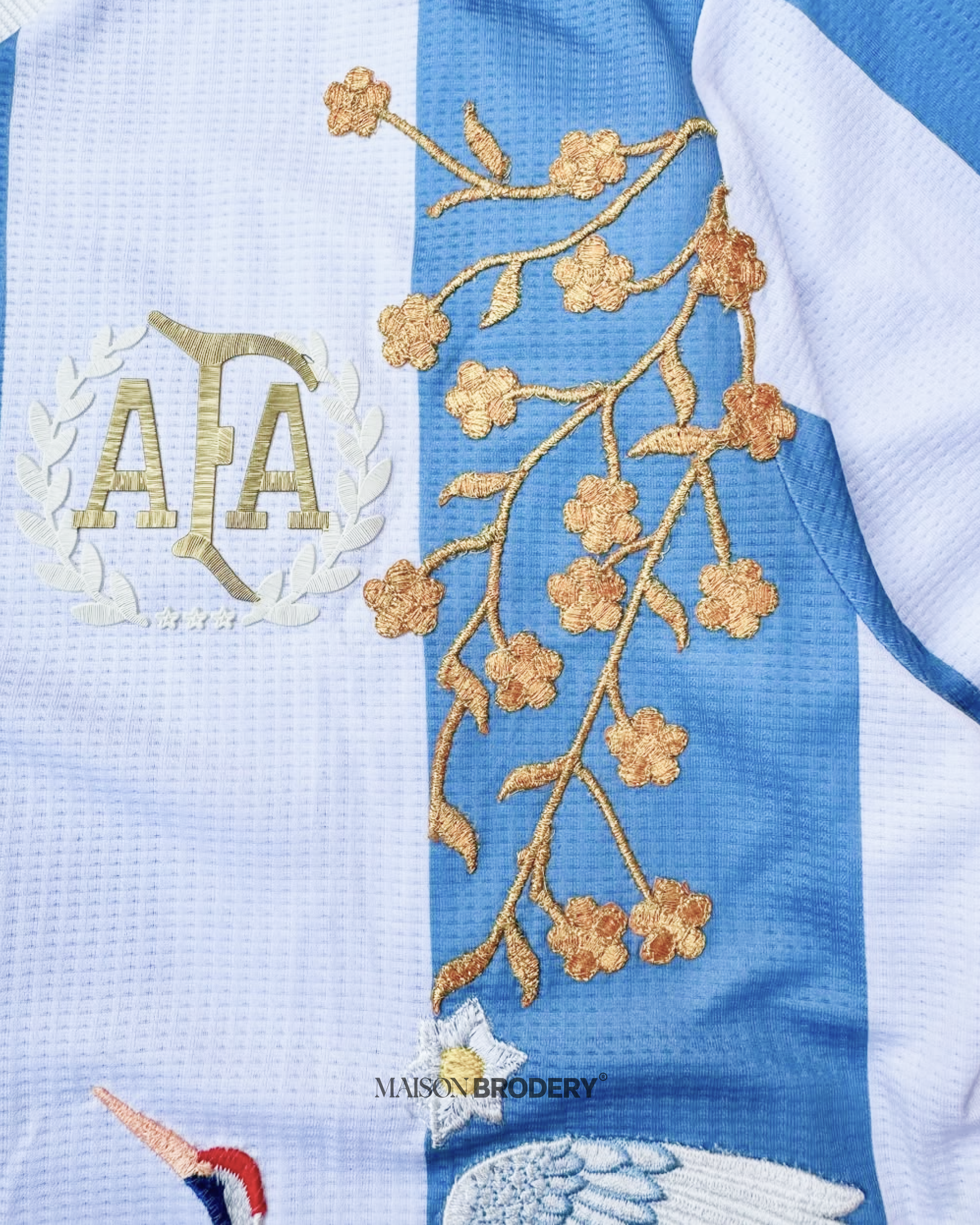 Floral gold embroidery on the Embroidered Argentina 50th Anniversary featuring cherry blossom branches and crest details.