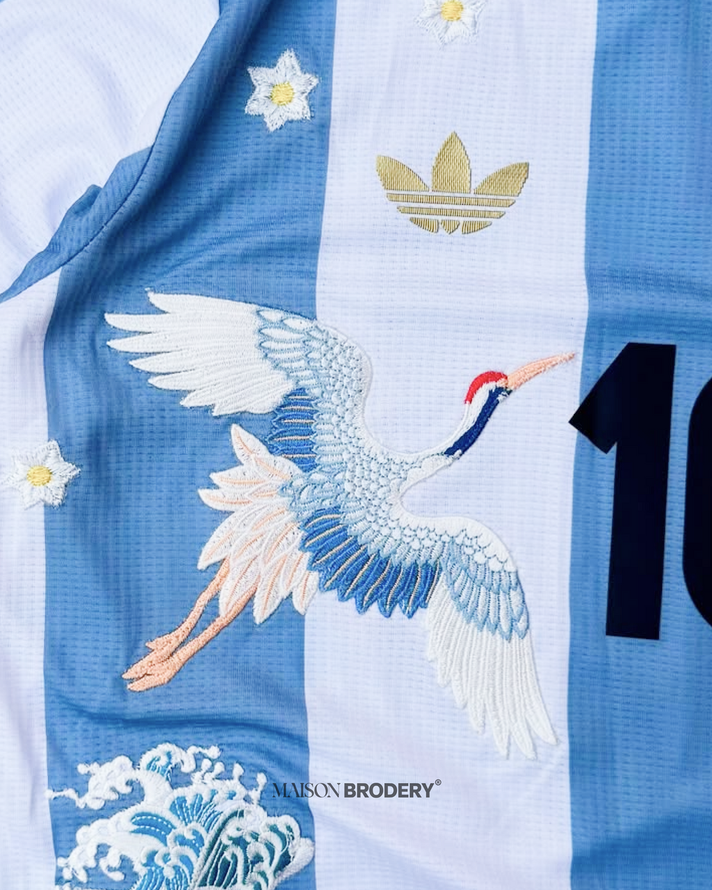Close-up of the Embroidered Argentina 50th Anniversary showing crane stitching, golden trefoil and star details.