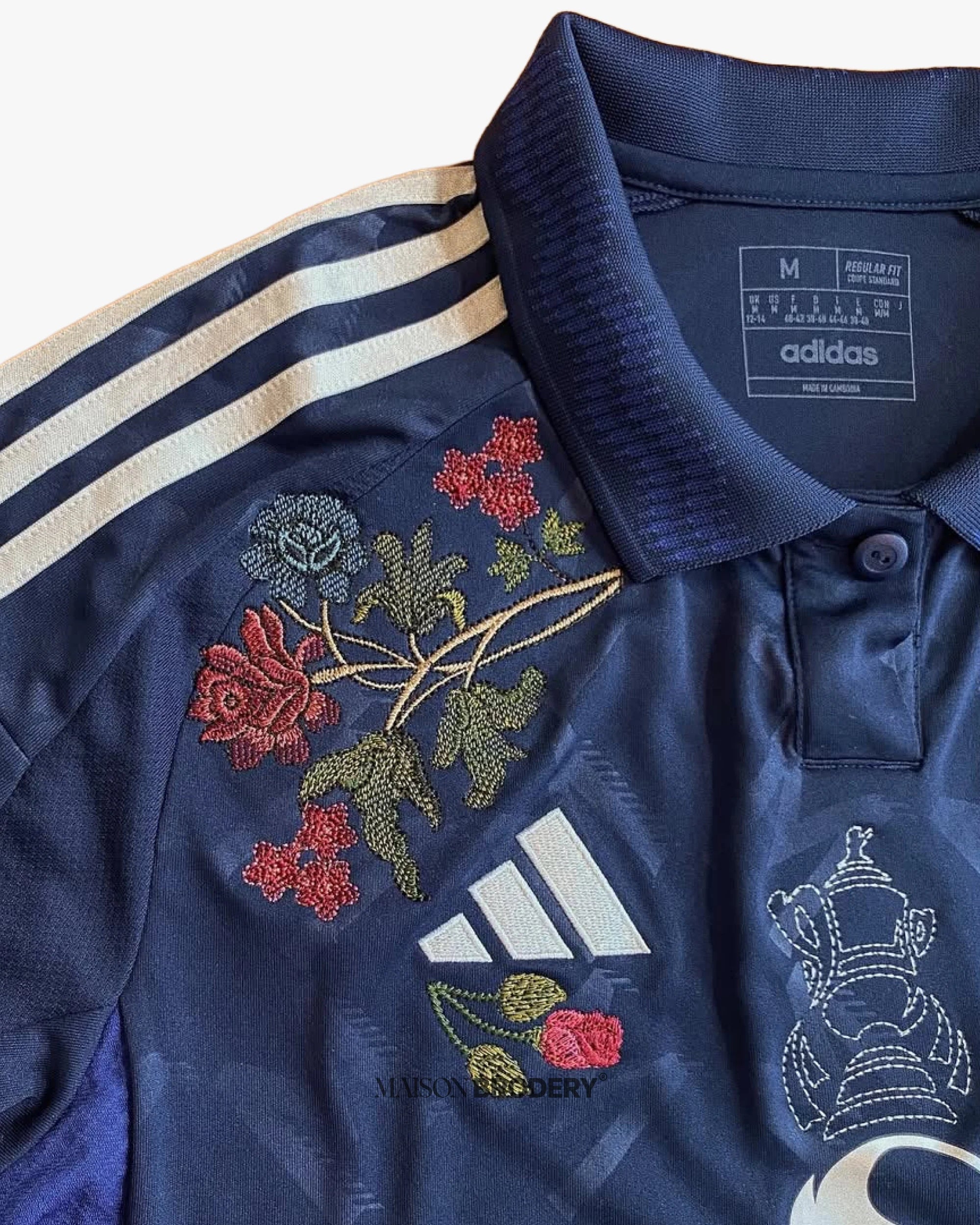 Floral embroidery on the Embroidered Manchester United Away Jersey 2024-25 in red, blue and green tones.