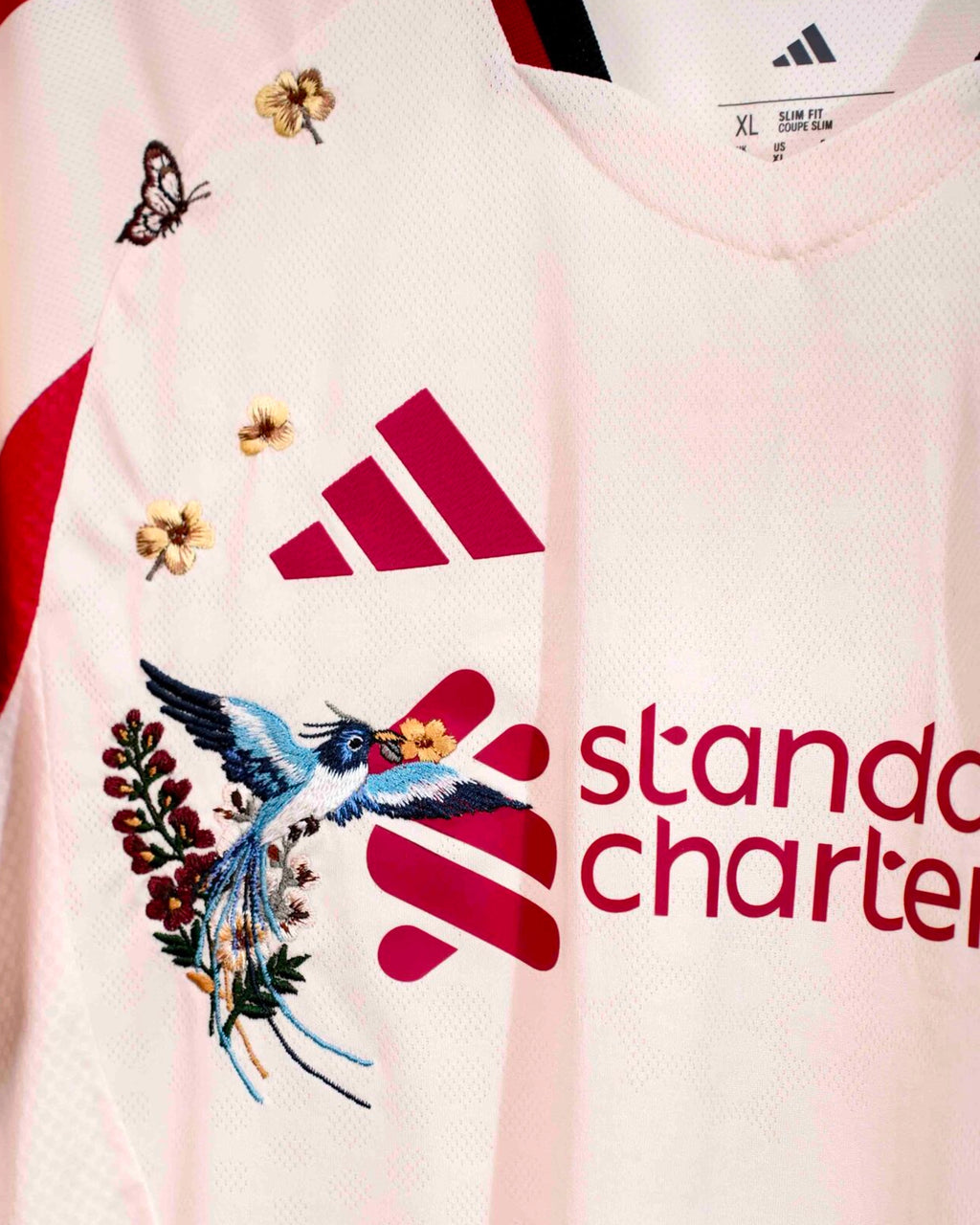 Detailed Embroidery Zoom Of The Liverpool 'England Botanical' Edition 2025-26 Long Sleeves Jersey Showcasing Intricate Red Rose Stitching Around The Club Crest And Sports Logo. This Liverpool Concept Jersey Highlights Bespoke Botanical Threadwork.